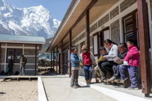 Children read and play outside the rebuilt classrooms at Shree Thame Basic School, Solukhumbu, Nepal.