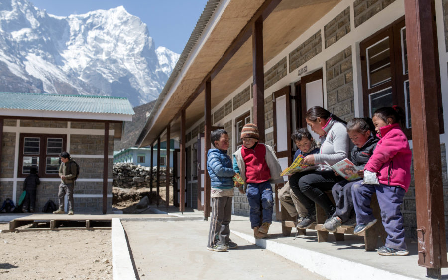 Children read and play outside the rebuilt classrooms at Shree Thame Basic School, Solukhumbu, Nepal.