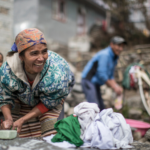 A smiling Nepalese woman hand-washing clothes